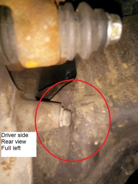 1996 Ford Bronco - A close-up rear view of the driver's side of a vehicle's suspension or braking system. A red circle highlights a bolt or fastener on a rust…