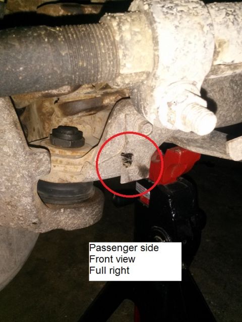 1996 Ford Bronco - A close-up view of the passenger side front suspension of a vehicle, showing a red circle around a damaged area on a metal bracket. The veh…