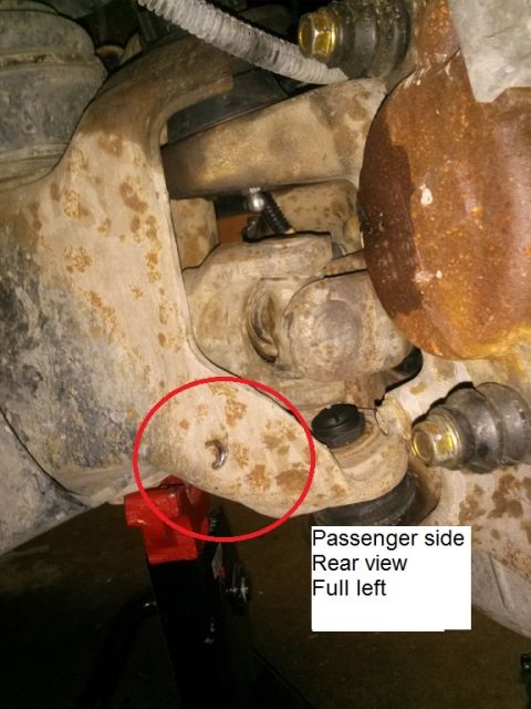 1996 Ford Bronco - A close-up view of the passenger side suspension of a 1996 Ford Bronco, showing a U-joint and a circled bolt on the control arm. The vehicl…