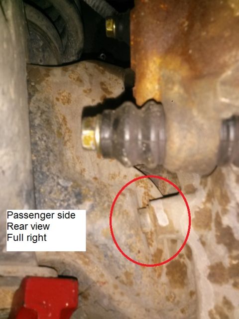1996 Ford Bronco - A close-up rear view of the passenger side suspension components of a vehicle, showing rusty metal and rubber boots. A red circle highlight…