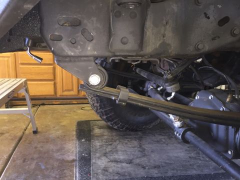 1988 Ford Bronco - The underside of a vehicle shows a suspension component with a shock absorber and leaf springs attached to the axle. A steering linkage is…