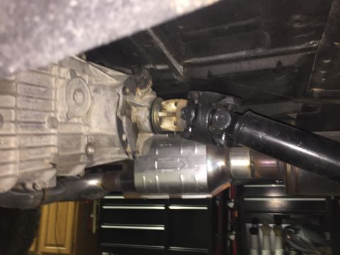1988 Ford Bronco - The underside of a vehicle shows a transmission, a driveshaft connected to a transfer case, and a catalytic converter. The vehicle appears…