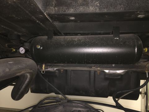 1988 Ford Bronco - The underside of a vehicle shows a black cylindrical air tank mounted horizontally with a pressure gauge attached to one end. A large exhau…