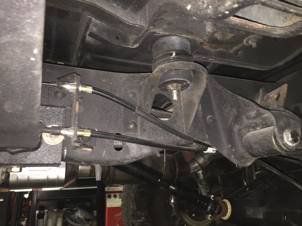 Underside view of vehicle frame with brake cables and rubber mount.