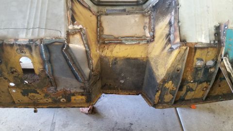 1979 Ford Bronco - This is a close-up, overhead view of a heavily modified and welded vehicle chassis, likely the floor pan and firewall area, showing extensi…