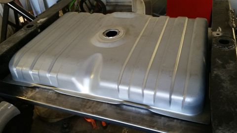 1979 Ford Bronco - A silver metal fuel tank is installed in the chassis of a vehicle, secured by dark metal framing. The tank has several raised horizontal ri…
