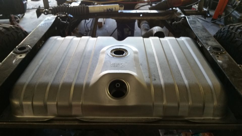 Silver aftermarket ribbed fuel tank installed under vehicle chassis.