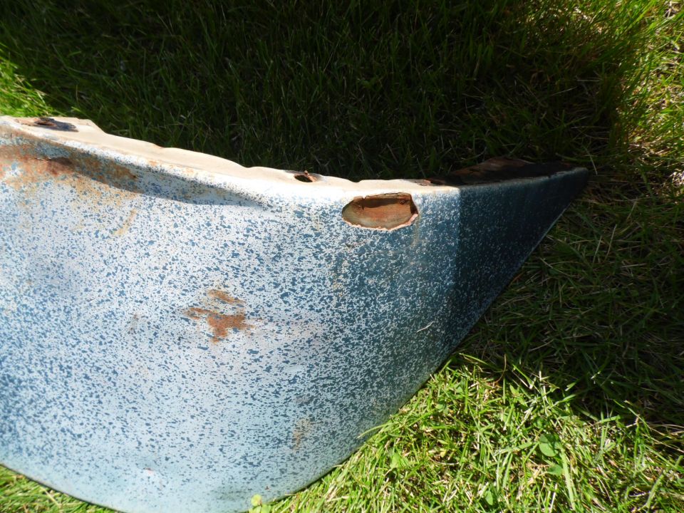 Rusty light blue vintage truck body panel with worn paint lying on green grass