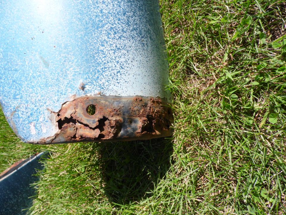 Rusted-through lower edge of a blue body panel from a 1950 Ford F2 lying on grass