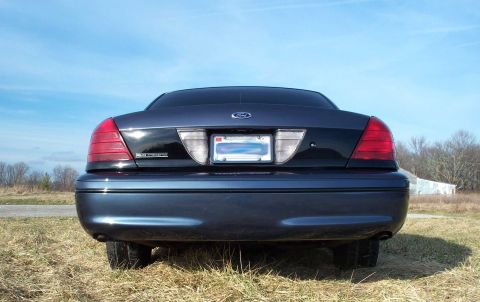 1998 Ford Crown Victoria - Rear view of a 1998 Ford Crown Victoria parked outdoors on a grassy area under a clear blue sky.