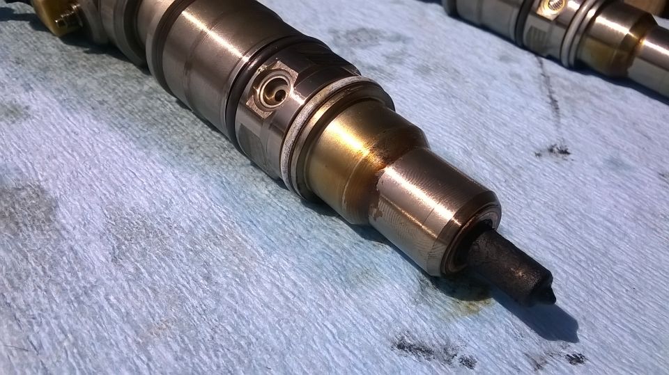 Diesel fuel injector with carbon buildup on a blue shop towel