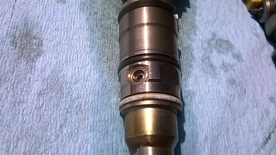 Close-up of a steel diesel injector component on a blue cloth