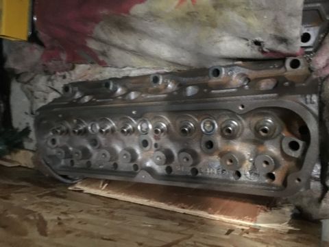 1993 Ford Bronco - A cast iron engine cylinder head with multiple valves and ports is shown resting on a wooden surface. The head appears to be for a V8 engin…