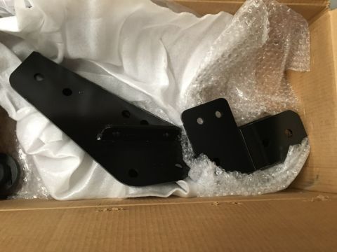 1993 Ford Bronco - Two black metal brackets are shown inside a cardboard box, partially wrapped in white protective material and bubble wrap. The brackets hav…