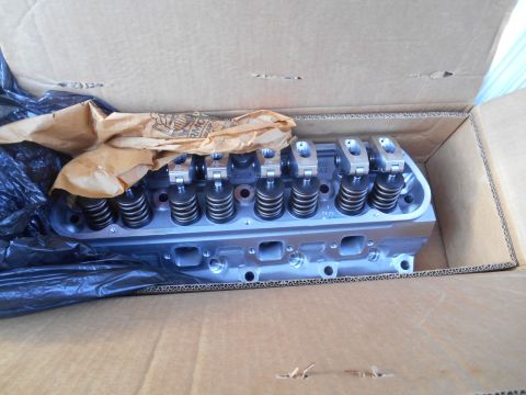 1972 Ford Bronco - A pair of aluminum cylinder heads with rocker arms and valve springs are shown inside a cardboard box, partially covered by brown paper and…