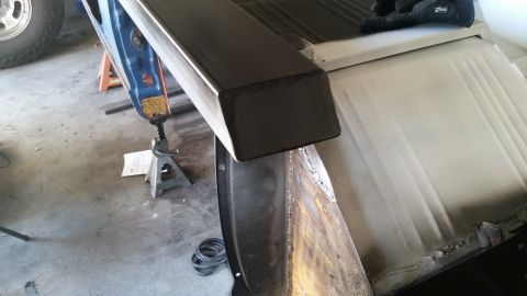 1979 Ford Bronco - A close-up view of a dark metal step or rail being fitted onto the side of a vehicle. The vehicle appears to be undergoing restoration or m…