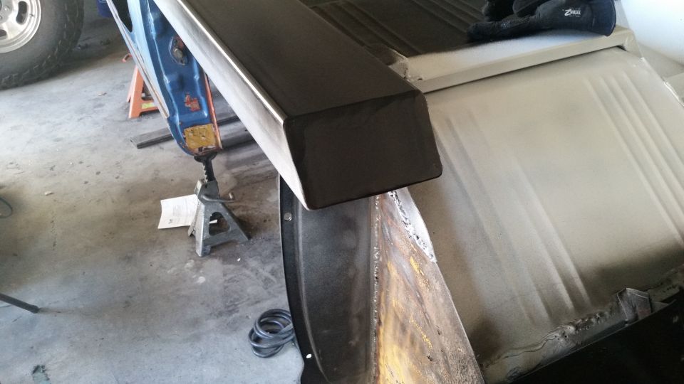 Close-up of a dark metal step being installed on a vehicle side, showing welding.