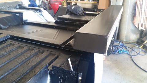 1979 Ford Bronco - The black painted bed of a vehicle, likely a truck or SUV, is shown with a newly installed black metal rail along the top edge. The interio…