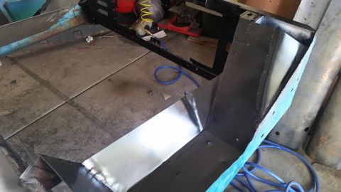 1979 Ford Bronco - A partially assembled vehicle frame, likely from a 1979 Ford Bronco, is shown in a workshop setting. The frame has been painted black and f…