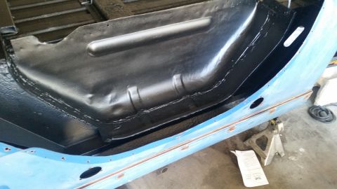 1979 Ford Bronco - The interior floor pan of a vehicle has been coated with a black protective material. The exterior rocker panel is painted blue and shows s…