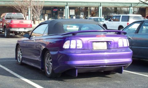 1998 Ford Crown Victoria - A purple convertible Mustang is parked in a lot with other vehicles visible.