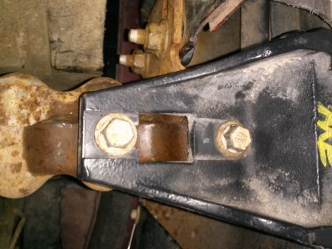 1996 Ford Bronco - A close-up view shows two bolts securing a black metal bracket to a rusted metal component. The bolts have hexagonal heads with markings in…