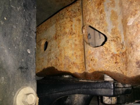 1996 Ford Bronco - A close-up view shows significant rust on the frame of a vehicle. A black rubber component is visible below the rusted frame, with a bolt s…