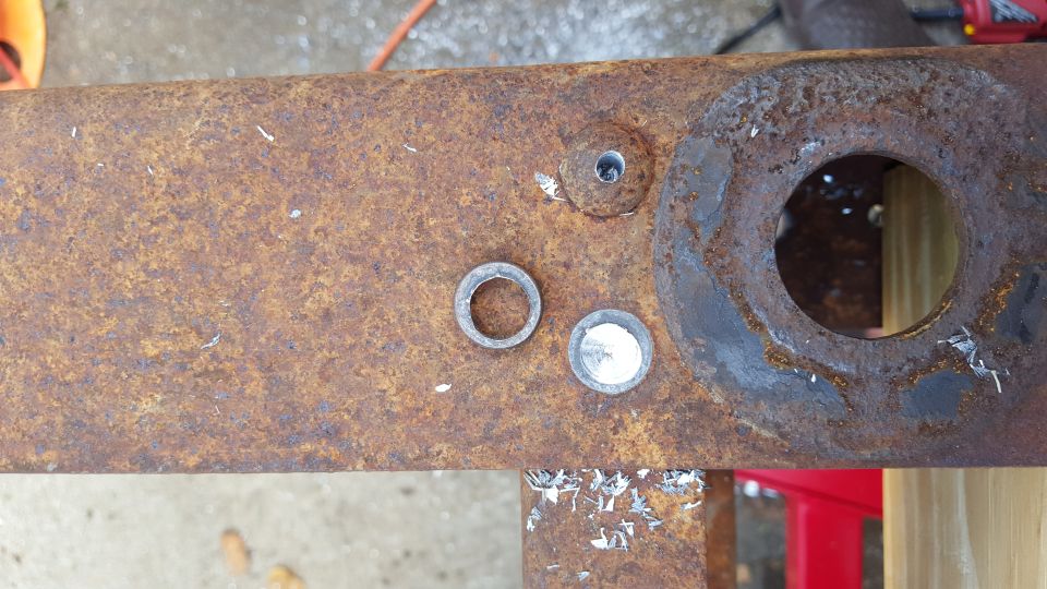 Close-up of rusty metal frame with washers and a drilled hole.