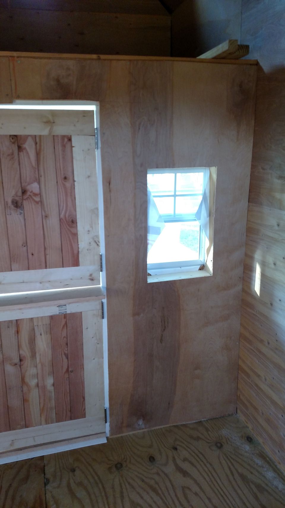 Plywood interior wall with a window and a board door