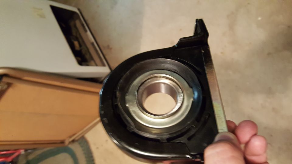 Black bearing support bracket with silver bearing, held by a hand.
