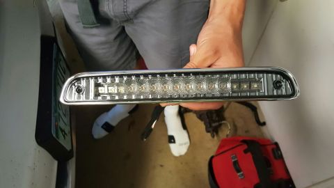 1996 Ford Bronco - A person holds a chrome-trimmed LED third brake light assembly with multiple clear lenses and visible LEDs. The assembly appears to be a re…
