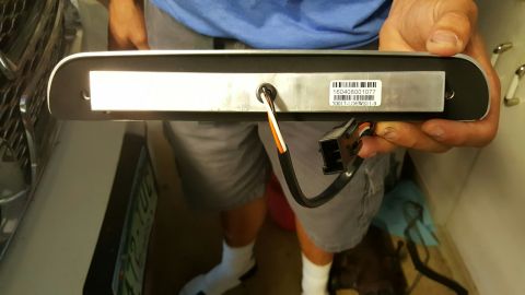 1996 Ford Bronco - A person holds a rectangular vehicle light fixture with a label and wiring harness attached. The label has a barcode and text that reads "1…