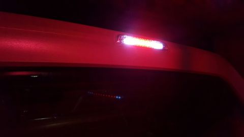 1996 Ford Bronco - The third brake light of a vehicle is illuminated with bright white LEDs. The vehicle's body is painted red and is seen from a rear angle a…