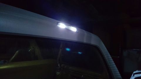 1996 Ford Bronco - Night shot of a rectangular cargo/dome lamp glowing bright white in the headliner trim above the rear side window of a hardtop SUV. The bri…