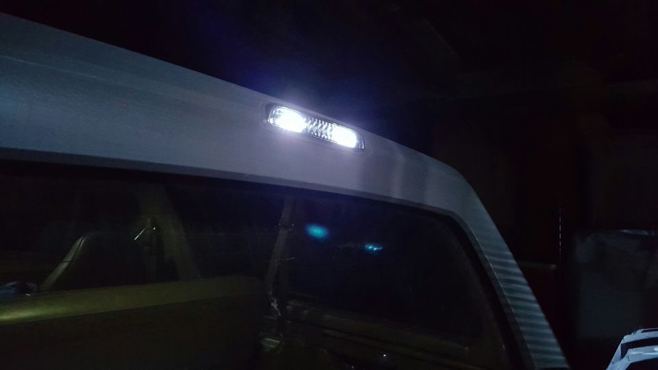 Bright white LED cargo lamp lit in the roof trim above a rear side window at night