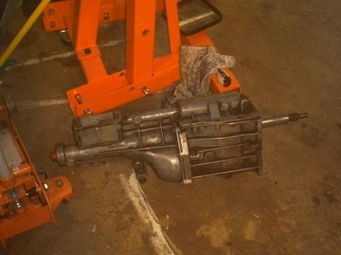 1991 Ford Crown Victoria - A transmission is shown on the floor with orange equipment in the background.