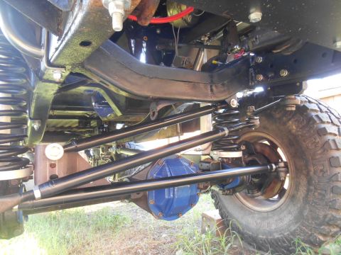 1972 Ford Bronco - The underside of a lifted vehicle, likely a Ford Bronco, showing the suspension and drivetrain components. Visible parts include the frame,…