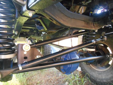 1972 Ford Bronco - The underside of a modified vehicle, likely a 1972 Ford Bronco, shows a heavy-duty suspension system with large black springs, blue-painted…