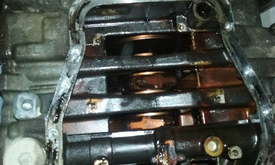 Close-up of an oily engine interior with crankshaft and connecting rods visible. "2.5L" marking on block.