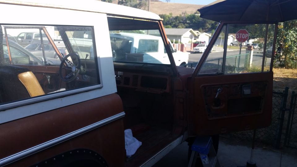 Interior and driver's side of an orange and white Ford Bronco with the door open.