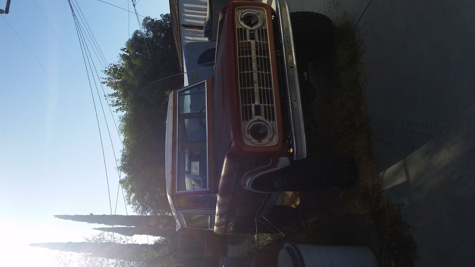 Sideways photo of a red and white vintage truck on a roadside