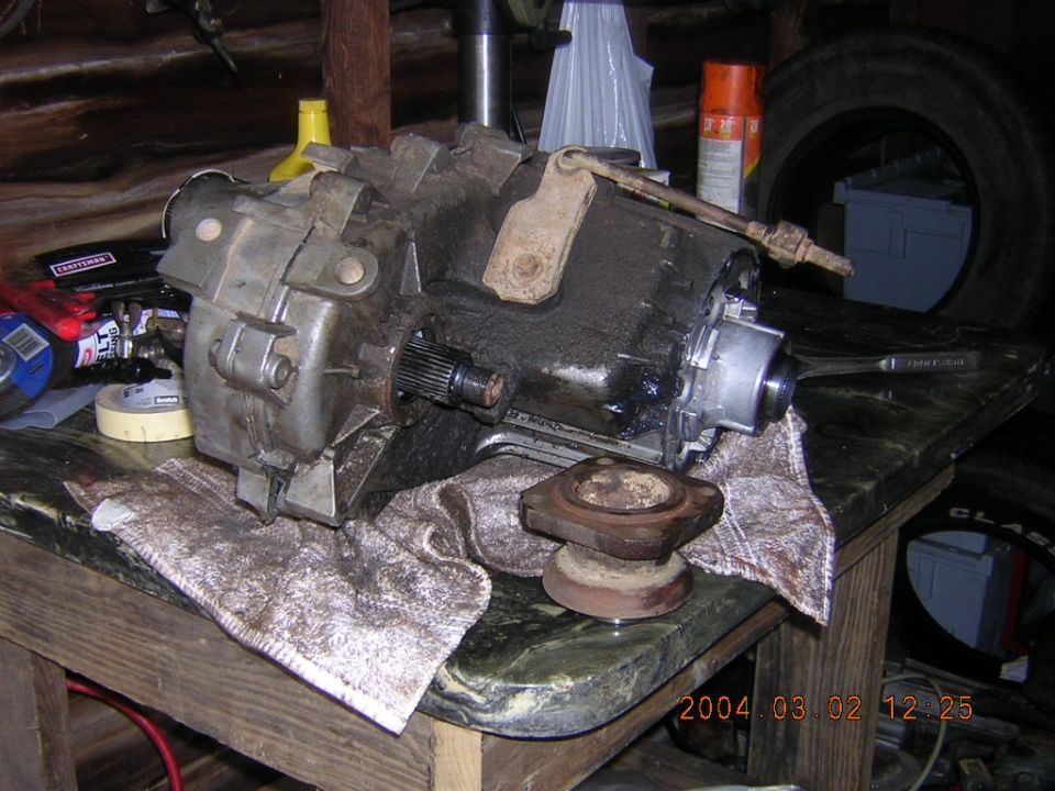Greasy transfer case on shop towel with output yoke on a workbench