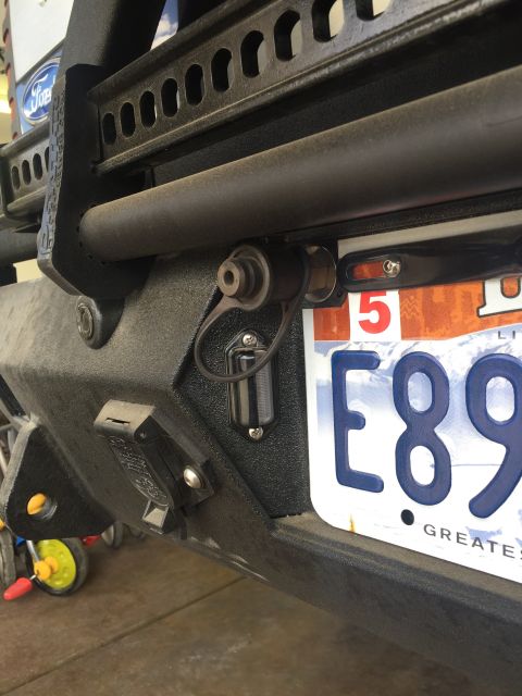 1988 Ford Bronco - Close-up of a vehicle's rear bumper, showing trailer hitch wiring and a license plate.