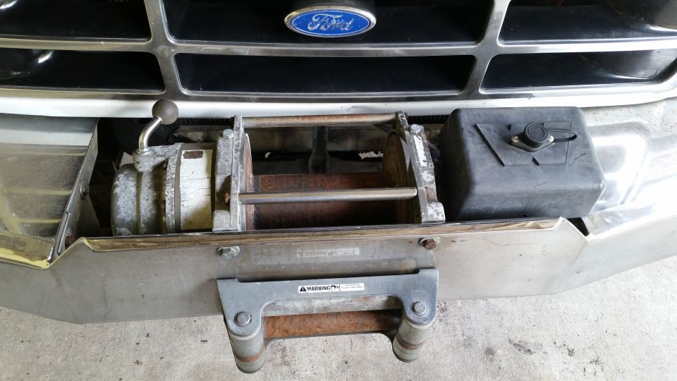 Ford truck front end with a winch mounted below the grille. Chrome bumper shows wear