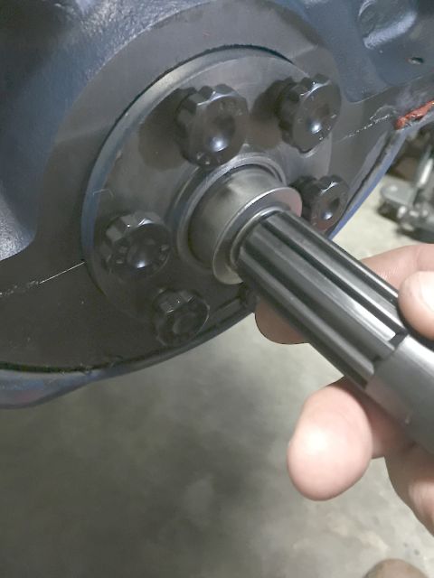 1978 Ford Bronco - A close-up view of a splined shaft being inserted into a housing with multiple bolts.