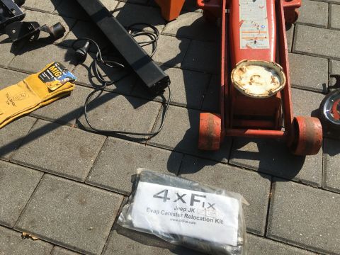 1979 Ford Bronco - Various automotive tools and a Jeep JK relocation kit are laid out on a paver patio.