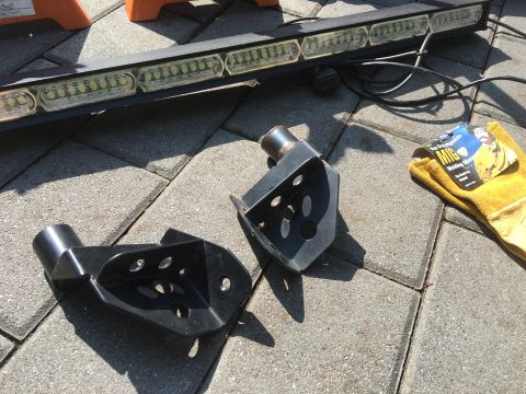 1979 Ford Bronco - Welding brackets and a light bar are laid out on a paved surface, with a pair of gloves nearby.