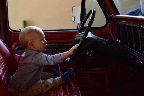 1978 Ford Bronco - A young child plays at the steering wheel of a 1978 Ford Bronco, offering a glimpse into the vehicle's interior.