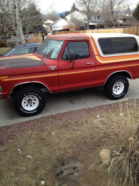 1978 Ford Bronco - This 1978 Ford Bronco is parked in a driveway, showing its side profile with distinctive stripe detailing.