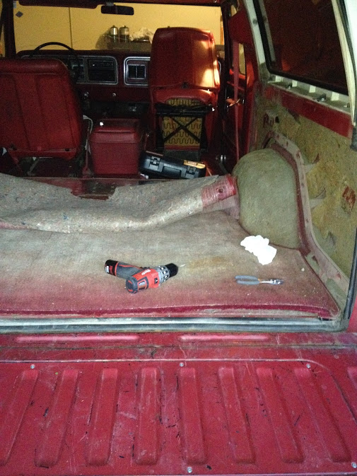 Interior view of a red SUV's cargo area and front seats, with a drill and screwdriver on the floor